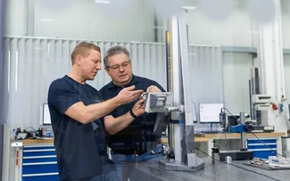 Zwei Mitarbeiter der Qualitätssicherung unterhalten sich über ein Bauteil