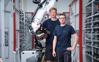 Zwei Mitarbeiter im Fräsen stehen vor einem Roboterarm