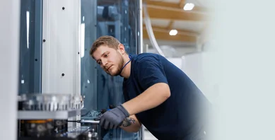Ein Mitarbeiter stellt eine Vorrichtung in einer Fräsmaschine an der Linearanlage ein.