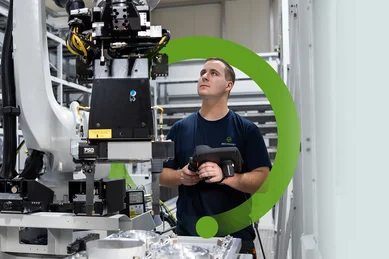 Ein Mitarbeiter im Fräsen beobachtet einen Roboterarm in einer Linearanlage