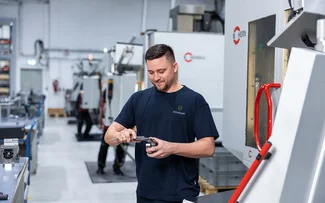 Ein Mitarbeiter im Fräsen misst ein Bauteil mit einem Messchieber vor einer CNC-Fräsmaschine