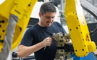 Ein Mitarbeiter im Drehen stellt einen Roboterarm ein