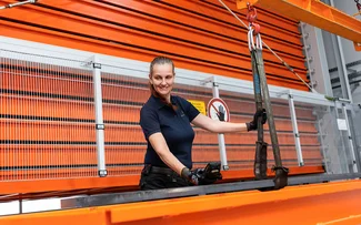 Eine Lagermitarbeiterin lagert Rohmaterialstangen ins Langgutlager ein