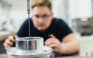 Ein Mitarbeiter der Qualitätssicherung bedient eine Messmaschine