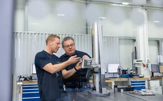 Zwei Mitarbeiter der Qualitätssicherung unterhalten sich über ein Bauteil