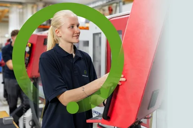 Eine Auszubildende steht an der CNC-Fräsmaschine in der Ausbildungswerkstatt