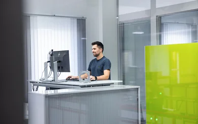 Ein Programmierer arbeitet an seinem höhenverstellbaren Schreibtisch