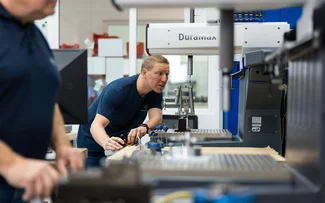 Ein Mitarbeiter der Qualitätssicherung misst ein Bauteil an einer Messmaschine