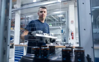 Ein Mitarbeiter legt Bauteile zur Bearbeitung in die Maschine ein