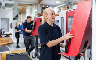 Eine Auszubildende steht an einer CNC-Fräsmaschine in der Ausbildungswerkstatt